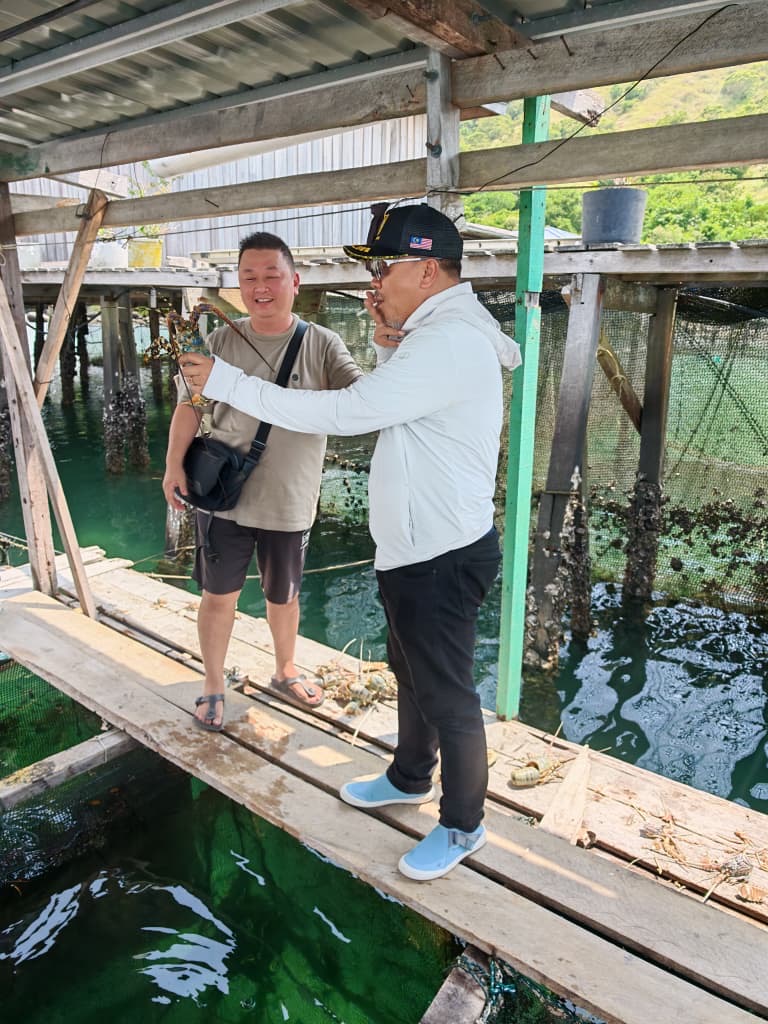 Delegation member holding a lobster during the technical tour
